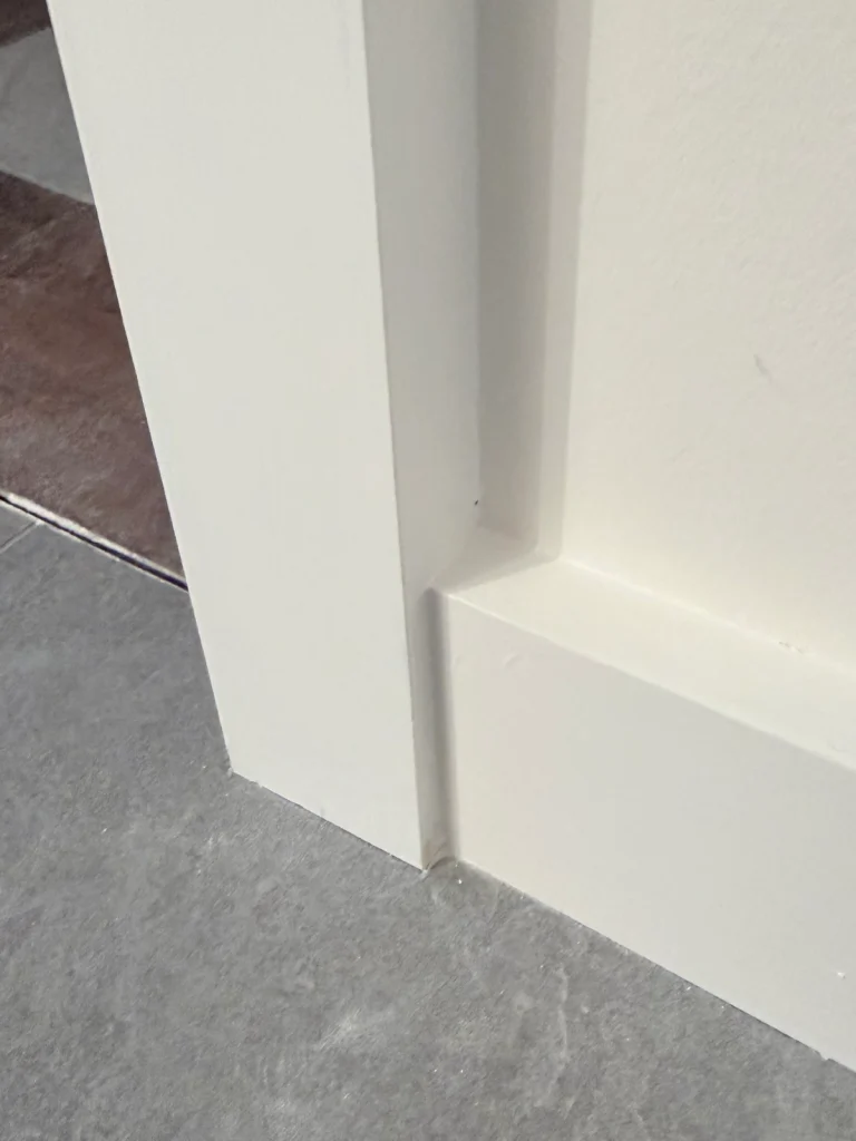 Baseboard meeting door casing in a finished bathroom showcasing precision finish carpentry